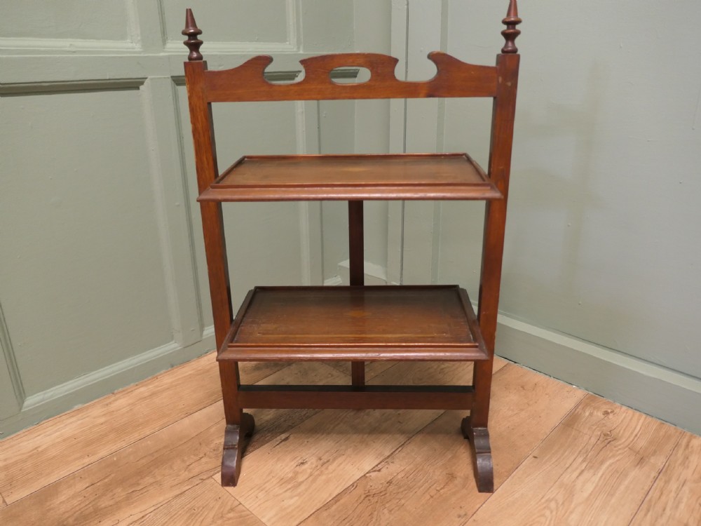 A warm brown mahogany metamorphic fire screen featuring turned finials that transforms into a two-tiered occasional butler table.