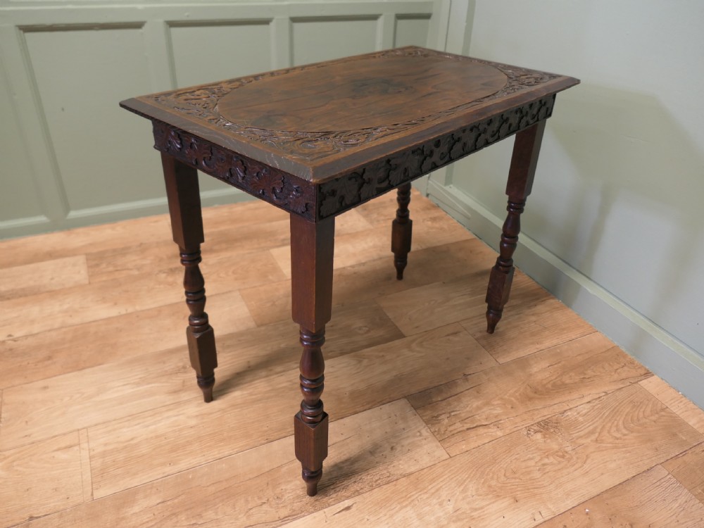 A rectangular dark elm side table featuring intricately carved Celtic scrollwork along the apron and tabletop border, supported by turned legs.