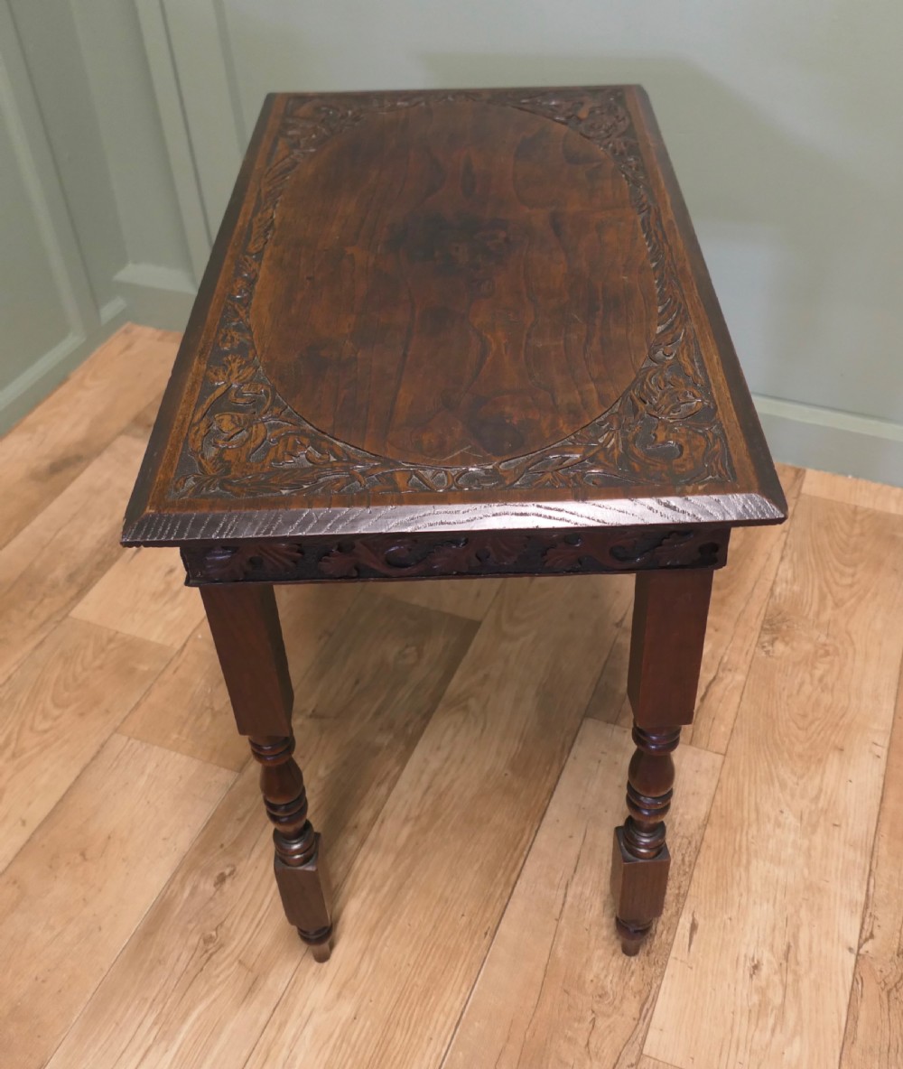 A rectangular dark elm side table featuring intricately carved Celtic scrollwork along the apron and tabletop border, supported by turned legs. View III
