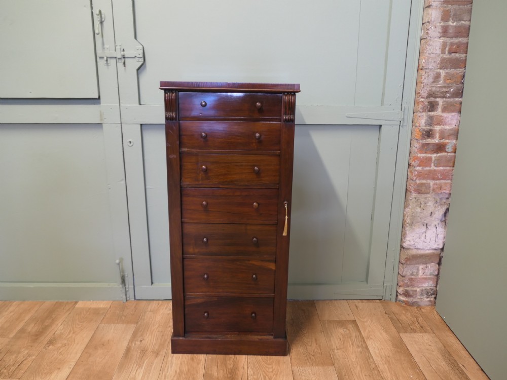 A tall Victorian mahogany Wellington chest featuring seven graduated drawers, turned wooden knob handles, and a side locking bar with a key. View II