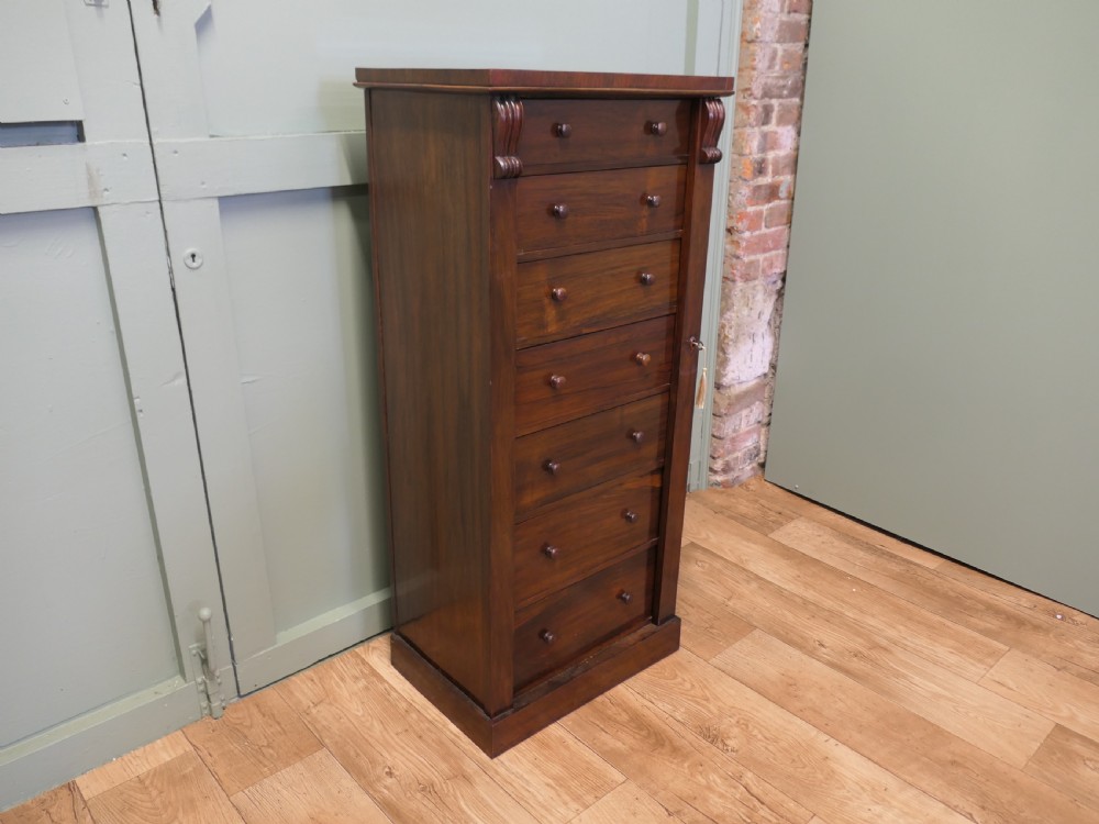 A tall Victorian mahogany Wellington chest featuring seven graduated drawers, turned wooden knob handles, and a side locking bar with a key. View III