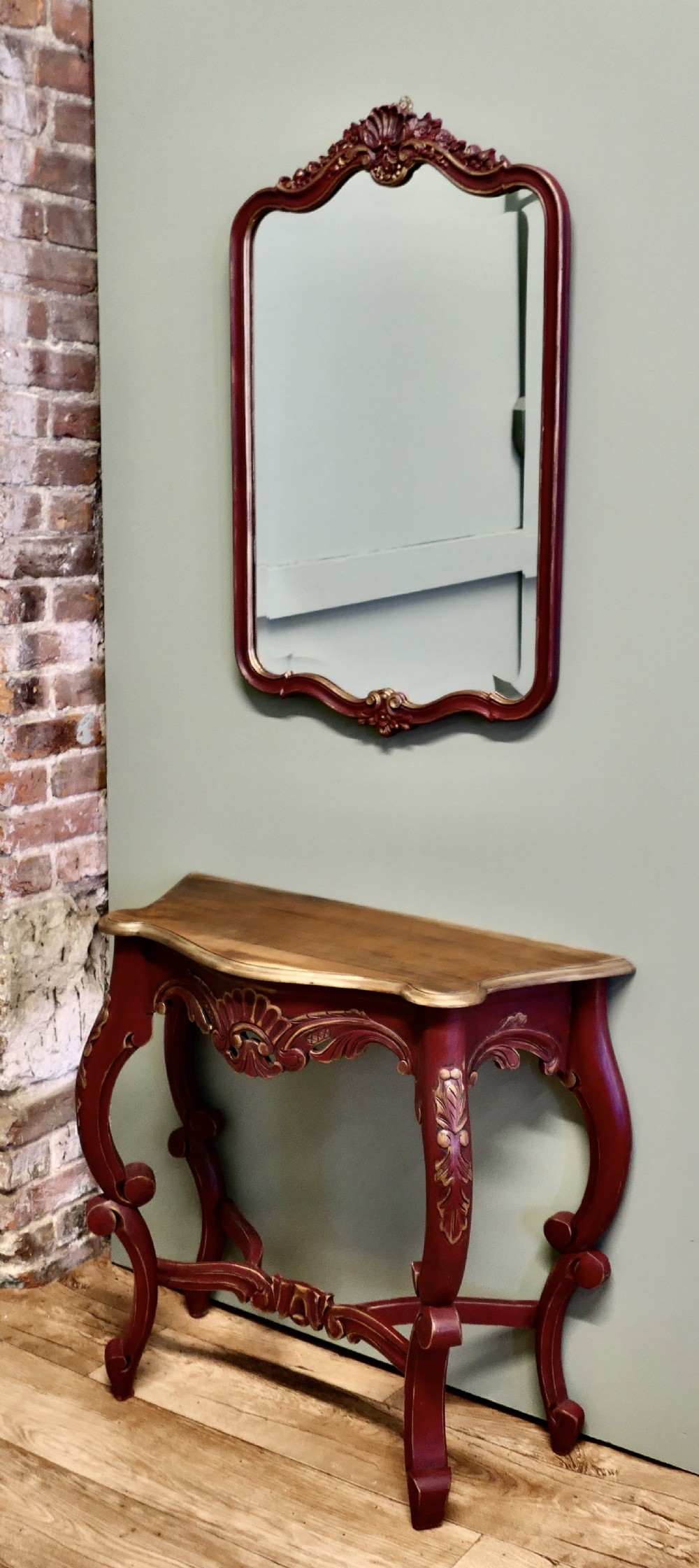 A red and gold painted French Louis XV style console table with a serpentine top and cabriole legs, accompanied by a matching carved wall mirror.
