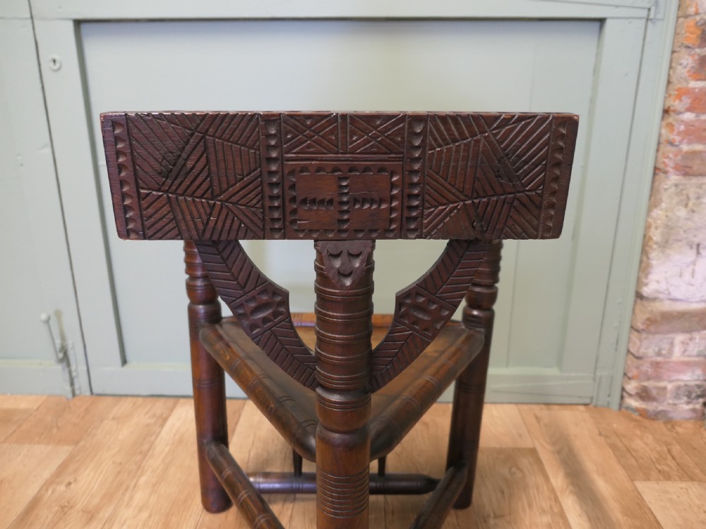 A 19th-century dark oak turners armchair with a triangular seat, heavily turned spindle posts, three legs, and a chip-carved top backrest. View III