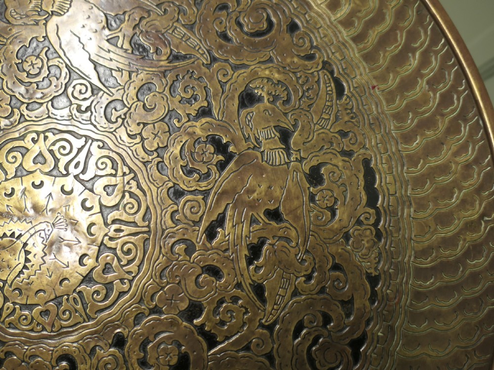 A circular Arts and Crafts side table with an embossed brass top displaying a peacock motif on a turned timber base. View IV