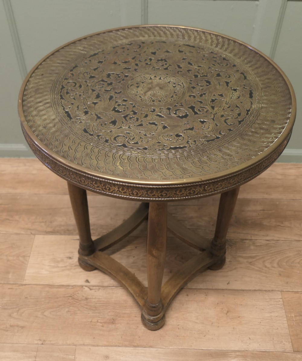 A circular Arts and Crafts side table with an embossed brass top displaying a peacock motif on a turned timber base. View V