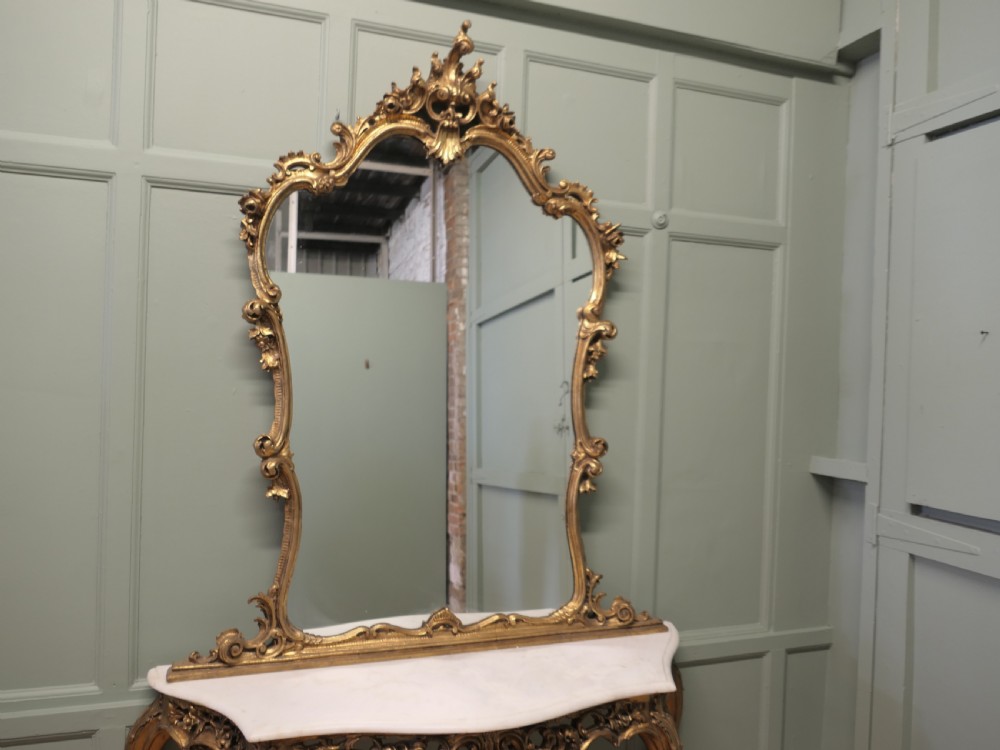 A 19th-century Italian giltwood console table featuring an ornate carved frame, cabriole legs, a white marble top, and a matching gilt-framed wall mirror. View II