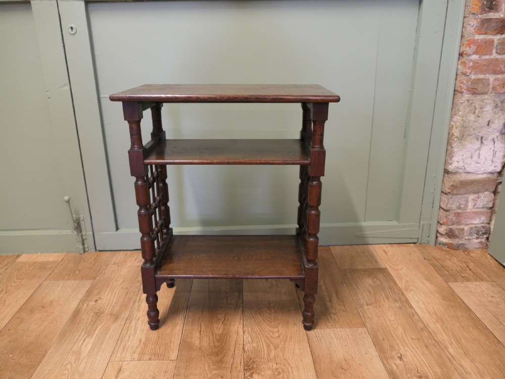 A dark oak three-tier Arts and Crafts side table featuring turned legs and spindled side galleries. View II