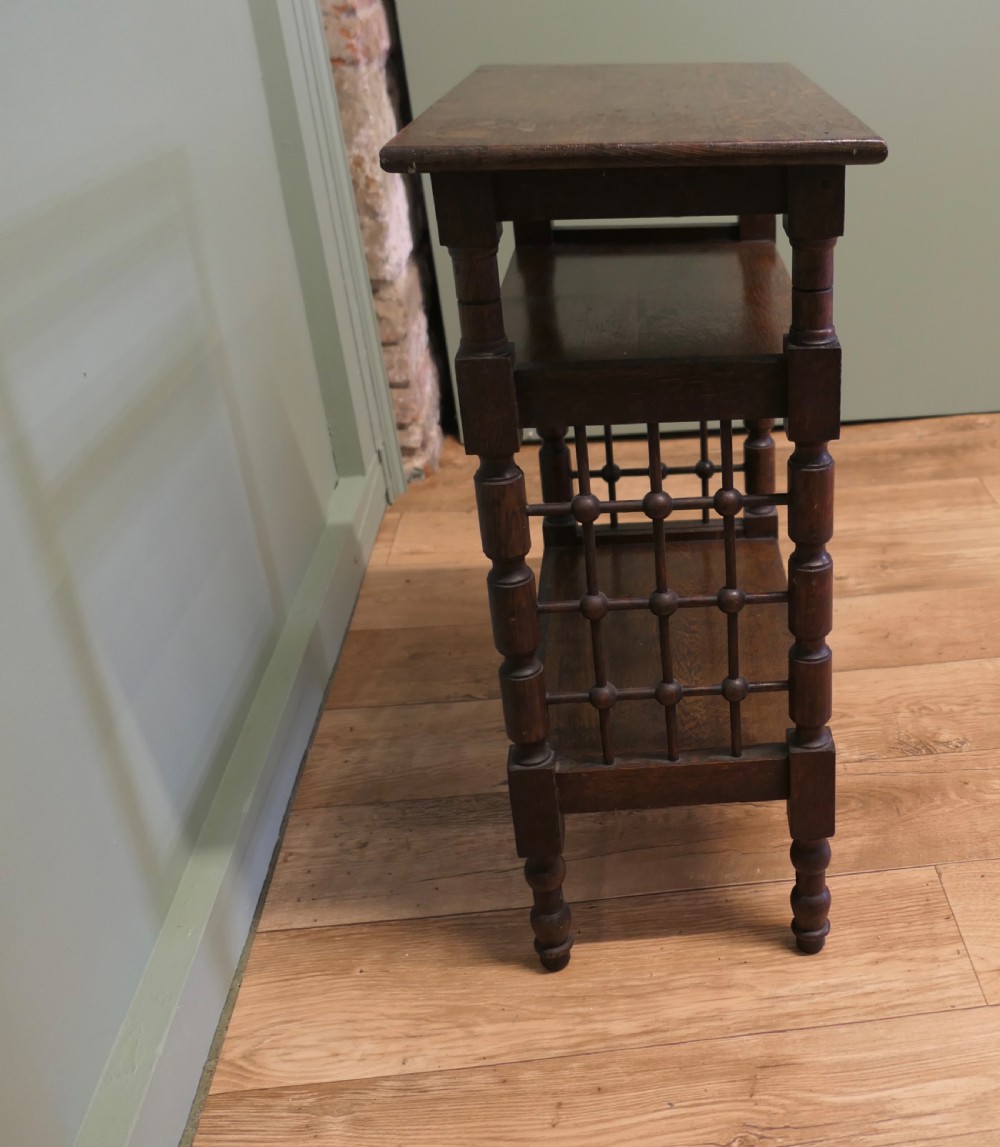 A dark oak three-tier Arts and Crafts side table featuring turned legs and spindled side galleries. View III