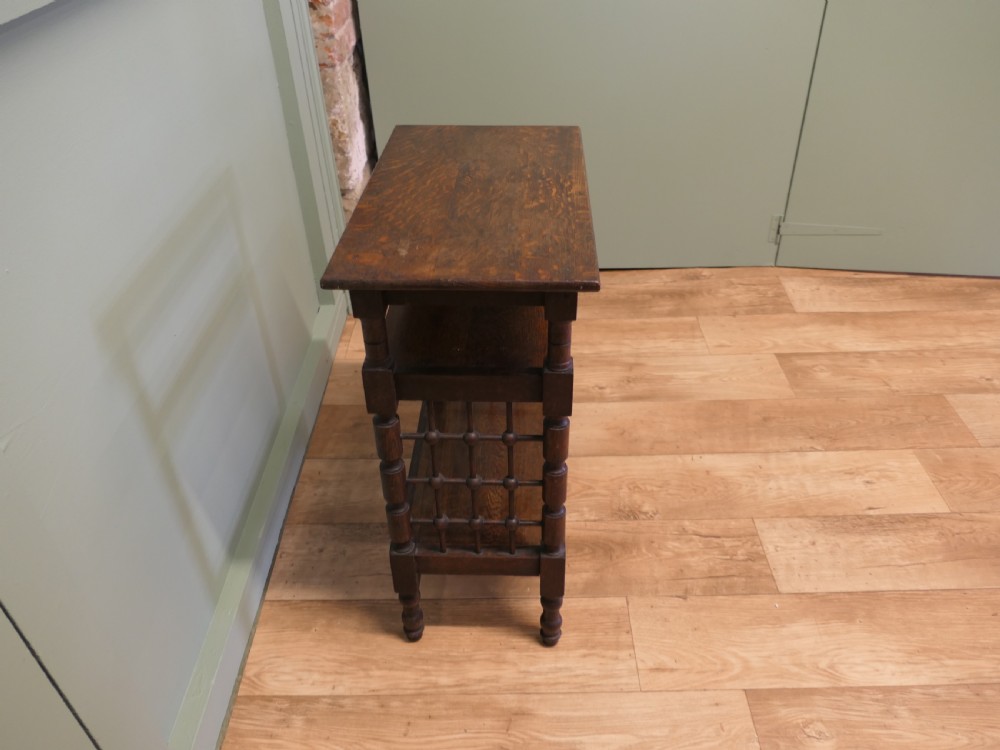A dark oak three-tier Arts and Crafts side table featuring turned legs and spindled side galleries. View IV