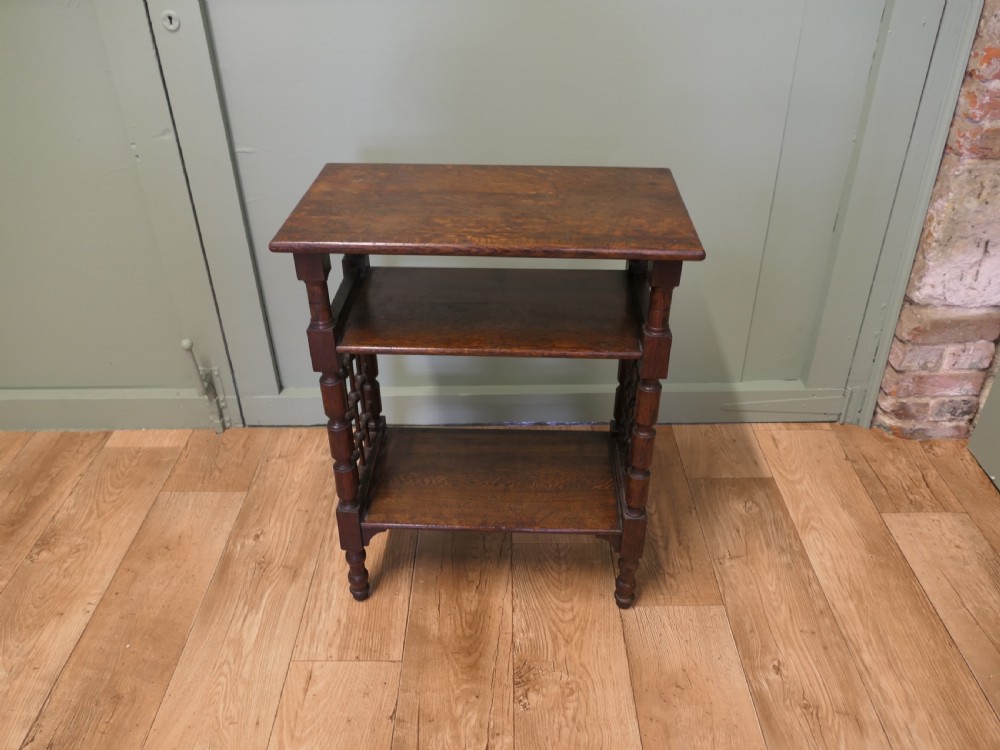 A dark oak three-tier Arts and Crafts side table featuring turned legs and spindled side galleries. View V
