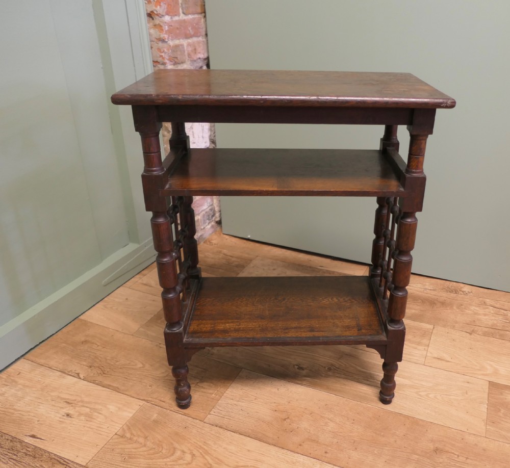 A dark oak three-tier Arts and Crafts side table featuring turned legs and spindled side galleries. View VI