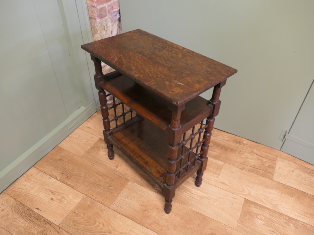 A dark oak three-tier Arts and Crafts side table featuring turned legs and spindled side galleries. View VII