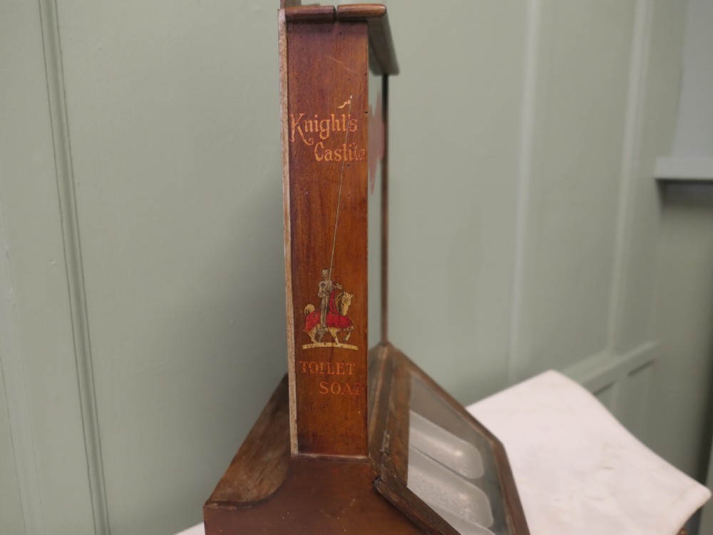An antique wooden countertop soap dispensing cabinet featuring glazed panels, red Knights Castile branding, and three metal lower dispensing compartments. View IV
