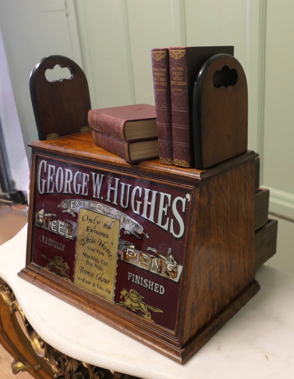 A Victorian mahogany shop counter display cabinet with a gilded reverse-painted glass panel advertising George W. Hughes steel pens. View III