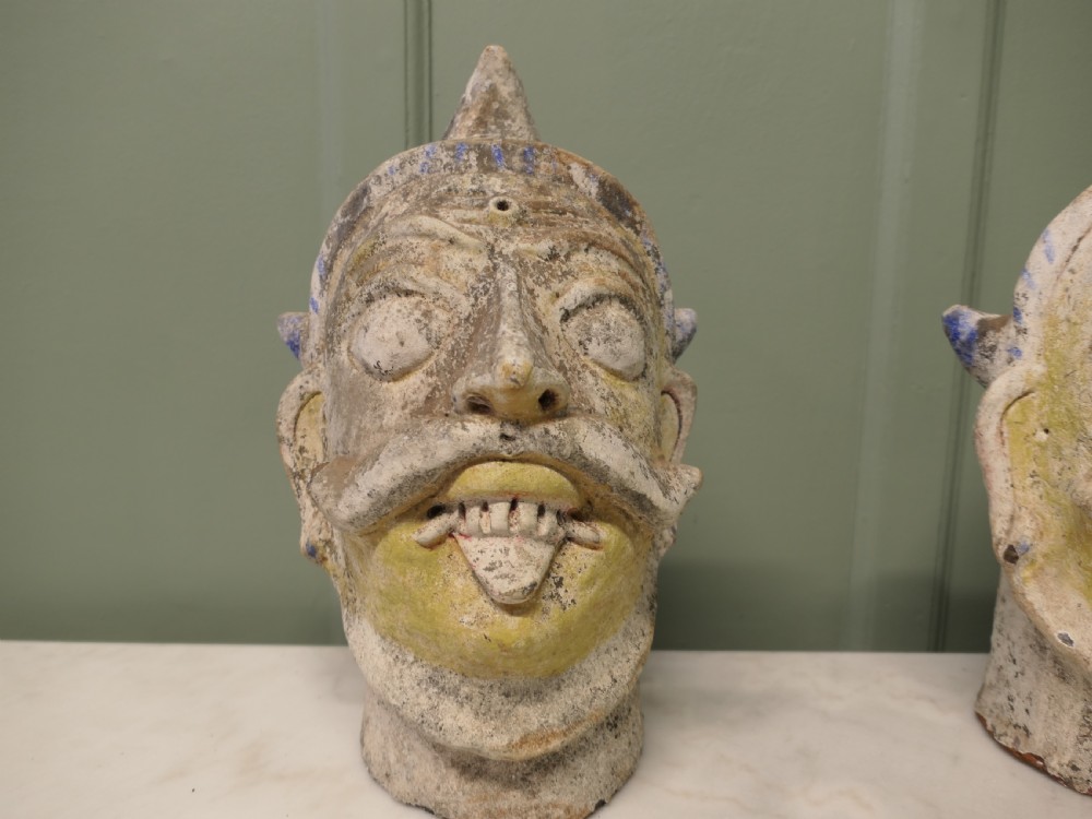 Pair of painted Indian terracotta tent pole tops sculpted as expressive facial heads with moustaches and conical crowns. View V