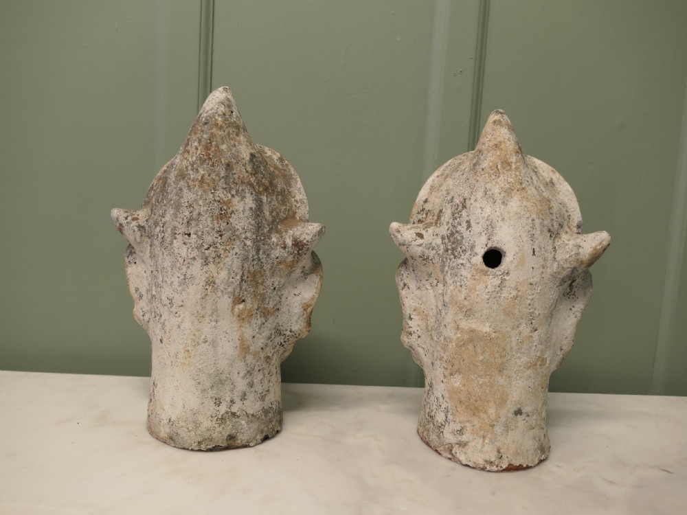 Pair of painted Indian terracotta tent pole tops sculpted as expressive facial heads with moustaches and conical crowns. View II