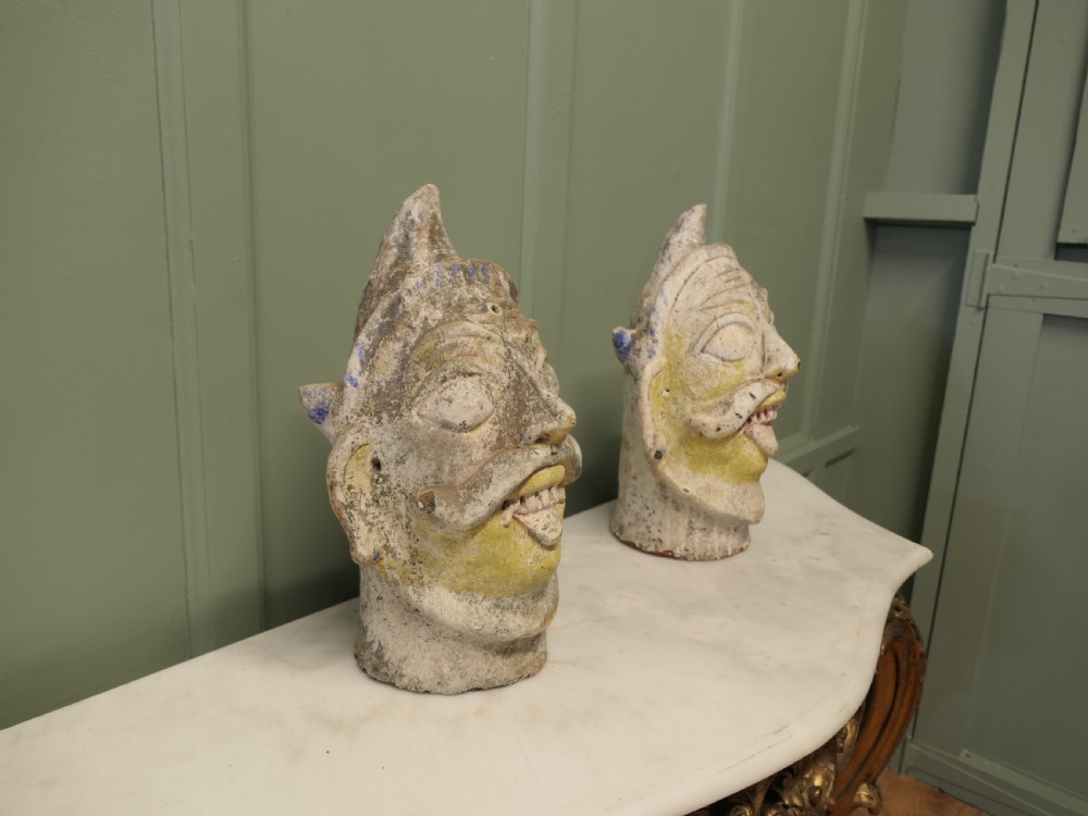 Pair of painted Indian terracotta tent pole tops sculpted as expressive facial heads with moustaches and conical crowns. View III