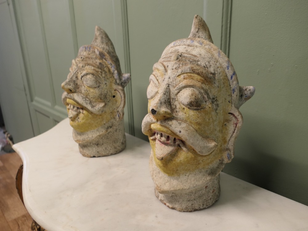 Pair of painted Indian terracotta tent pole tops sculpted as expressive facial heads with moustaches and conical crowns. View IV
