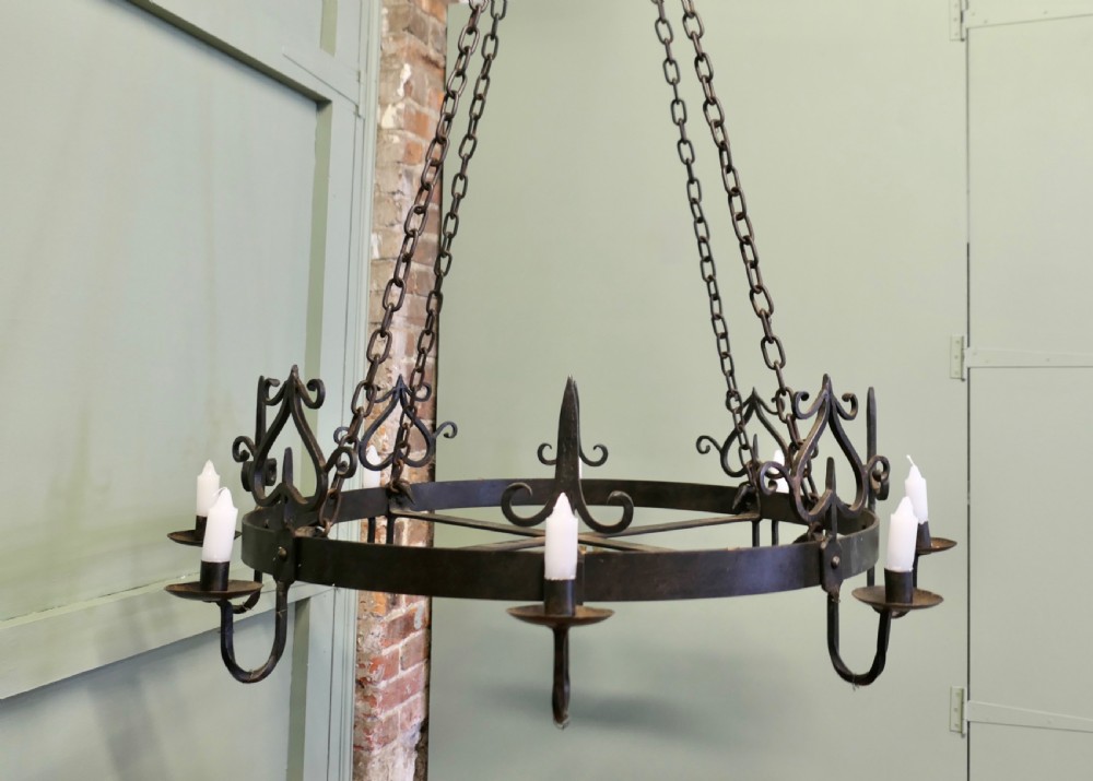 A large circular black wrought iron Gothic chandelier with candle sockets suspended by link chains. View III