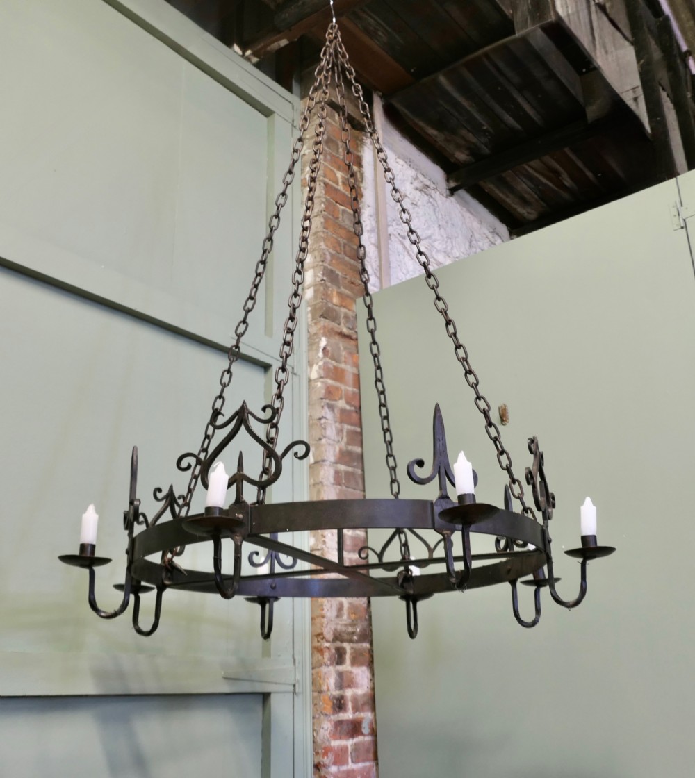 A large circular black wrought iron Gothic chandelier with candle sockets suspended by link chains. View IV
