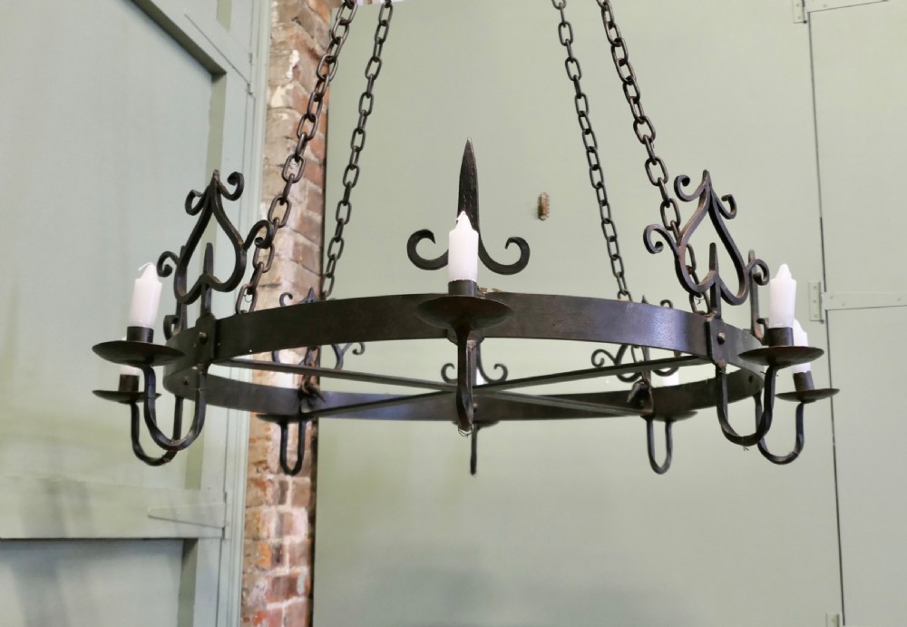 A large circular black wrought iron Gothic chandelier with candle sockets suspended by link chains. View V