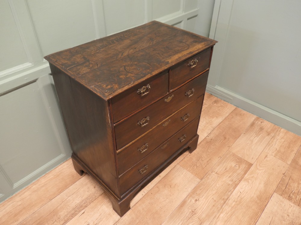 A late 18th-century Georgian dark oak chest of drawers featuring a two-short over three-long drawer configuration, brass drop handles, and bracket feet. View III