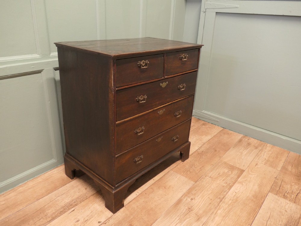 A late 18th-century Georgian dark oak chest of drawers featuring a two-short over three-long drawer configuration, brass drop handles, and bracket feet. View IV