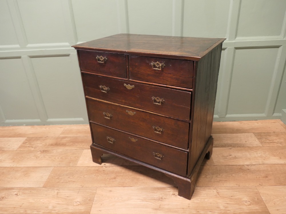 A late 18th-century Georgian dark oak chest of drawers featuring a two-short over three-long drawer configuration, brass drop handles, and bracket feet. View VII