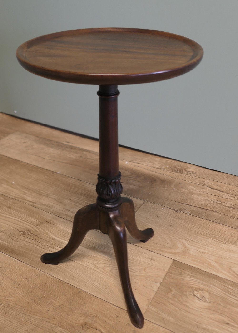 A small Victorian mahogany wine table featuring a circular dished top, a turned and carved central column, and three swept tripod legs.
