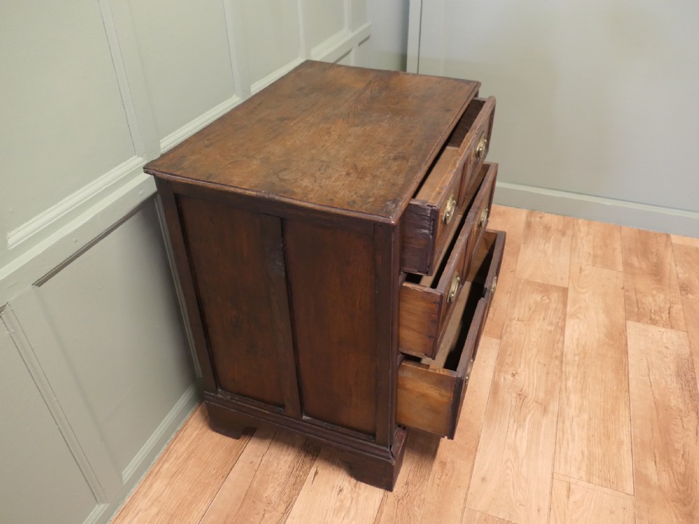 An 18th-century country elm chest of drawers with three moulded drawer fronts, brass drop handles, keyhole escutcheons, and bracket feet. View II