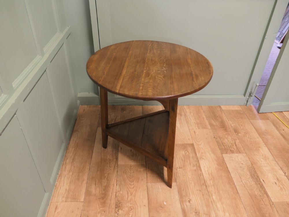 A Georgian oak cricket table featuring a circular top, three straight square legs, and a lower triangular under-shelf. View V