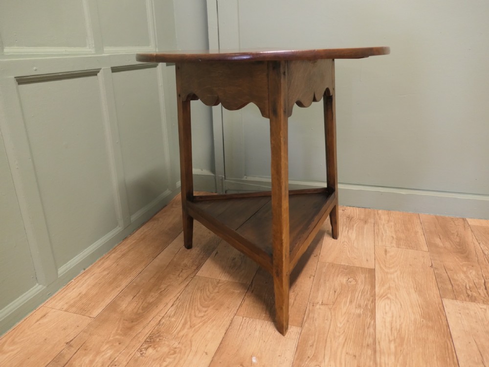 A Georgian oak cricket table featuring a circular top, three straight square legs, and a lower triangular under-shelf. View VI