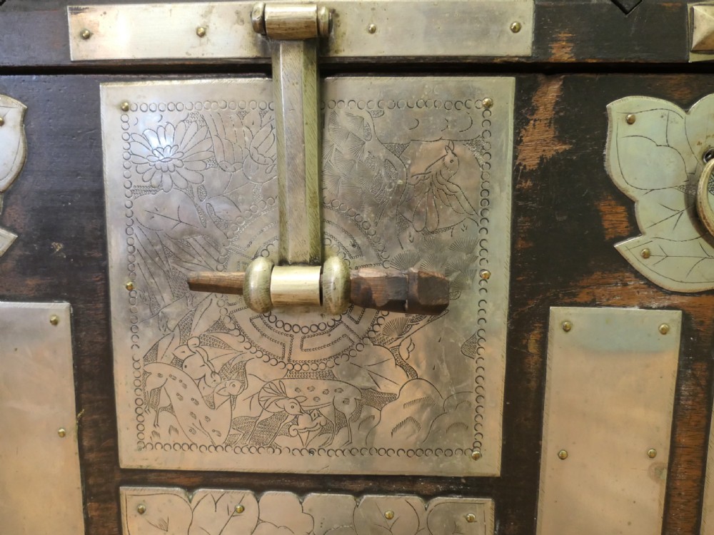A dark brown wooden Korean Bandaji chest adorned with elaborate silver-coloured brass plating, geometric studs, etched metal panels, and three top drawers. View III