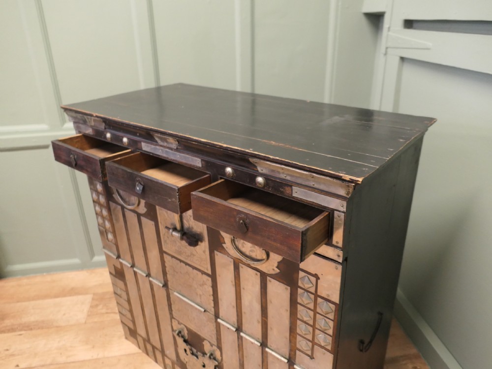 A dark brown wooden Korean Bandaji chest adorned with elaborate silver-coloured brass plating, geometric studs, etched metal panels, and three top drawers. View VIII