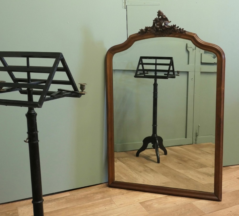 A tall wooden wall mirror featuring an arched frame topped with a carved cresting detail. View III