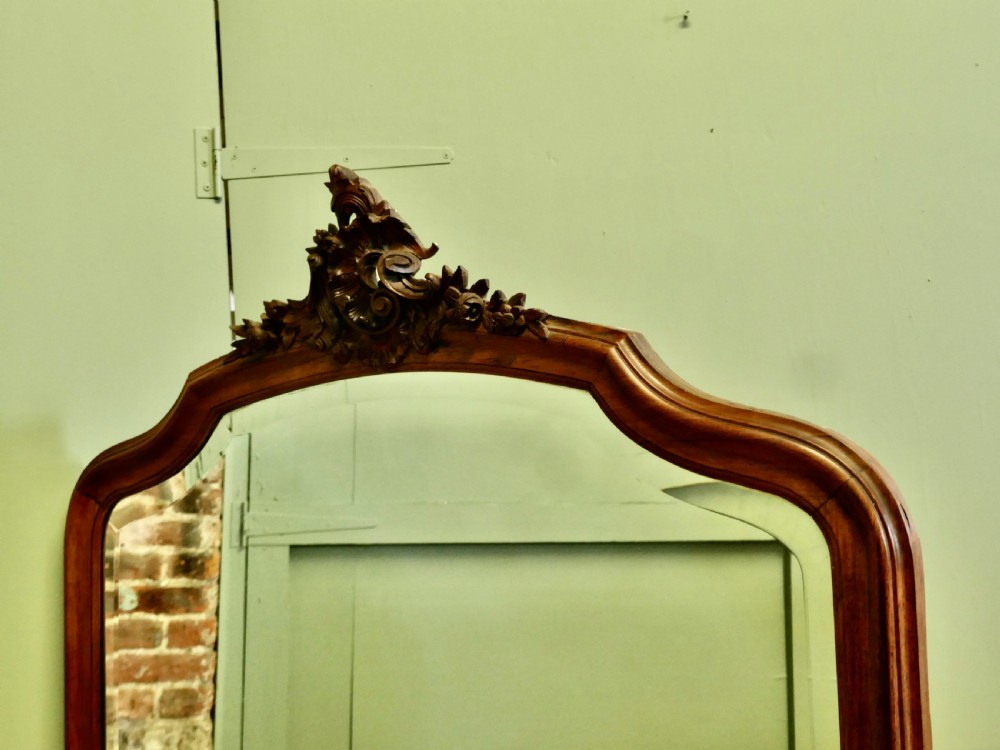 A tall wooden wall mirror featuring an arched frame topped with a carved cresting detail. View IV