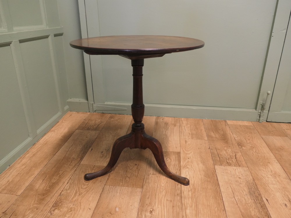 A circular solid oak tilt-top table with a turned central pedestal resting on three cabriole tripod feet. View II
