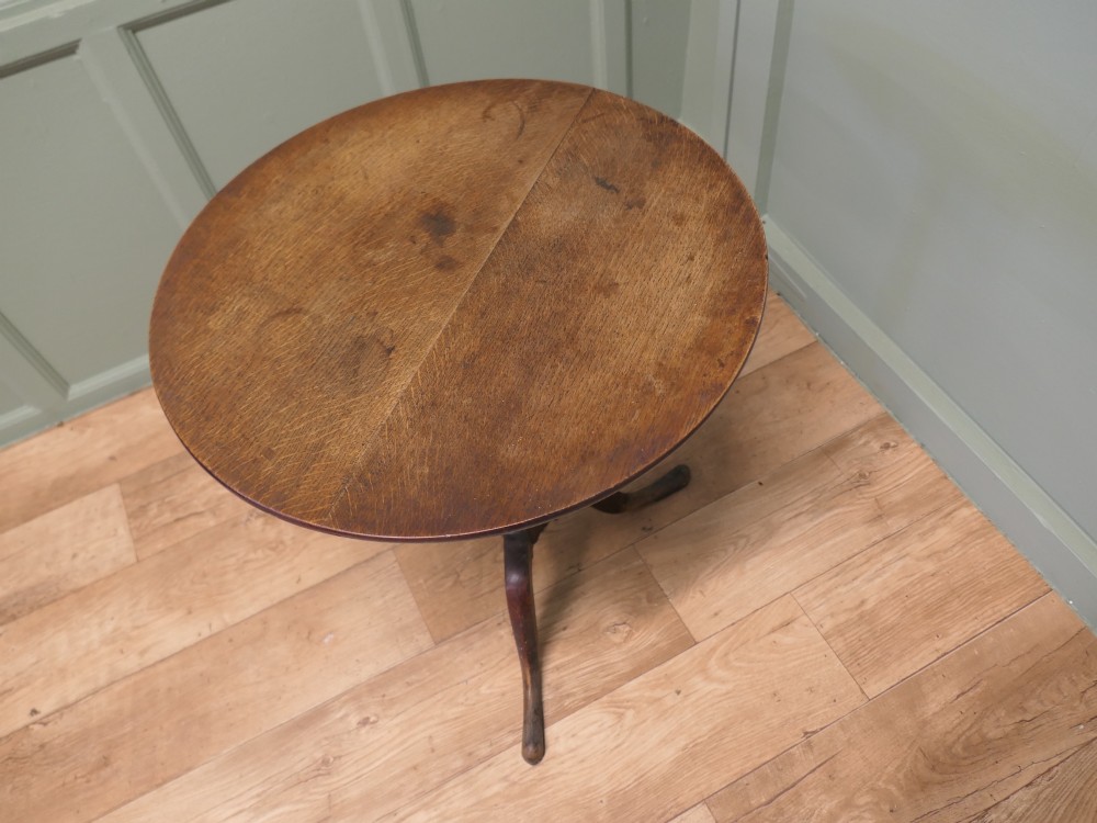 A circular solid oak tilt-top table with a turned central pedestal resting on three cabriole tripod feet. View IV