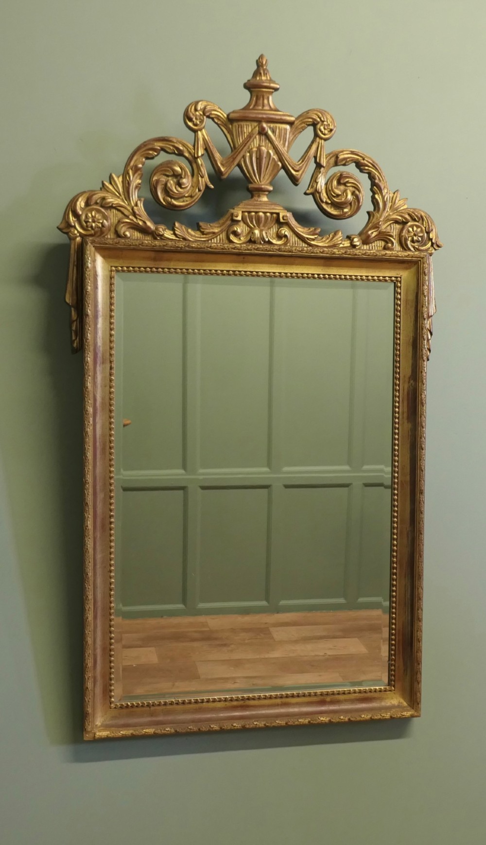 A rectangular French Napoleon III wall mirror featuring a gilded wood frame with a beaded inner edge and an elaborate carved top crest depicting an urn flanked by scrollwork.