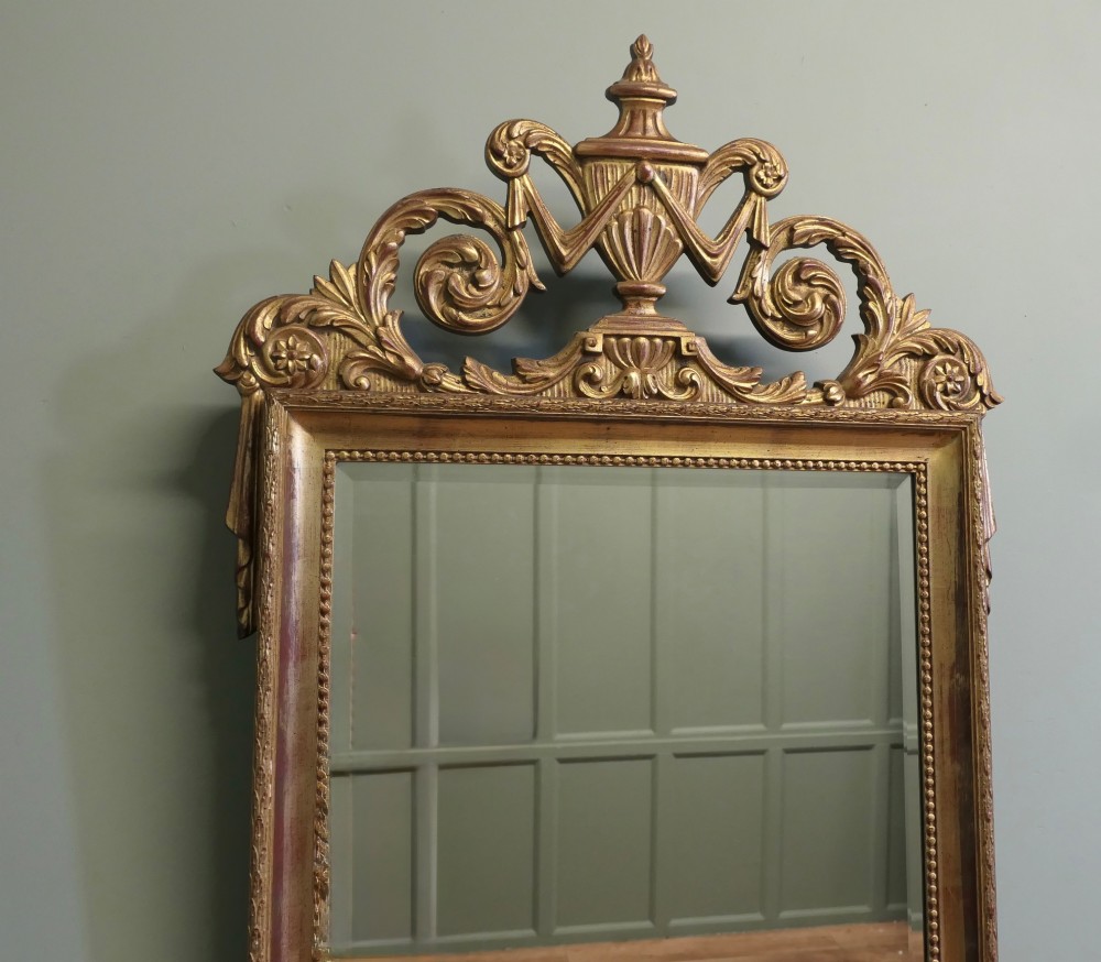 A rectangular French Napoleon III wall mirror featuring a gilded wood frame with a beaded inner edge and an elaborate carved top crest depicting an urn flanked by scrollwork. View II