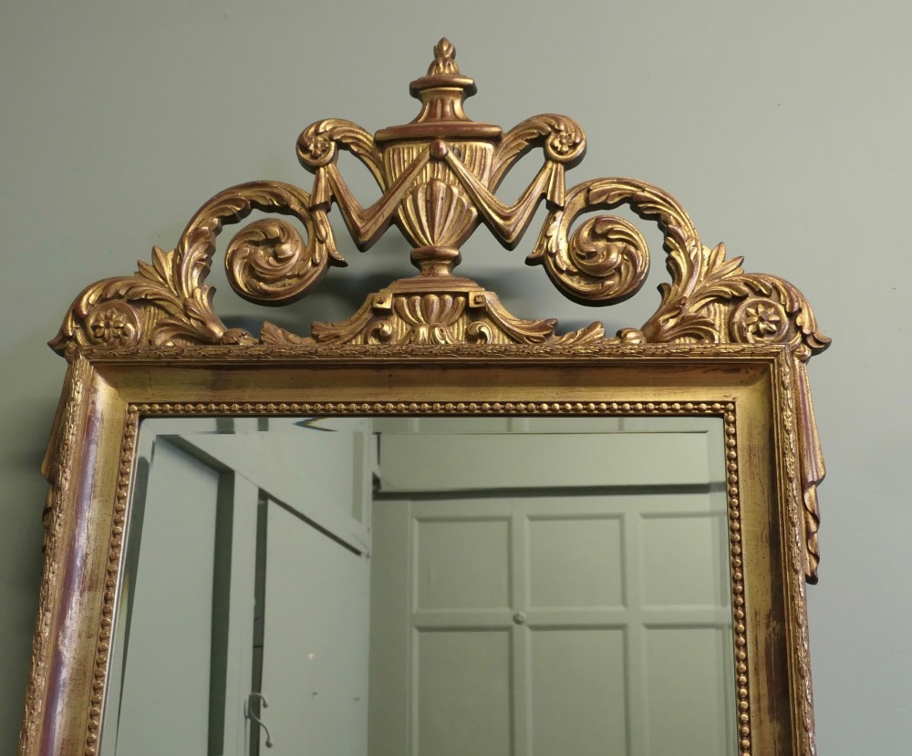 A rectangular French Napoleon III wall mirror featuring a gilded wood frame with a beaded inner edge and an elaborate carved top crest depicting an urn flanked by scrollwork. View III