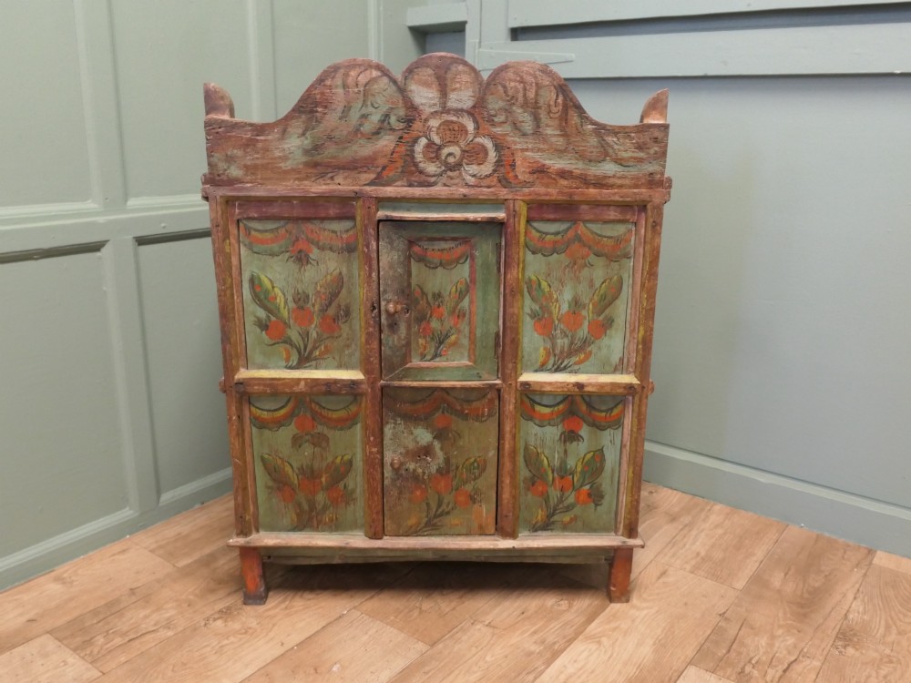 A rustic French folk art painted pine cupboard with green and orange floral panels and a scalloped gallery top. View III