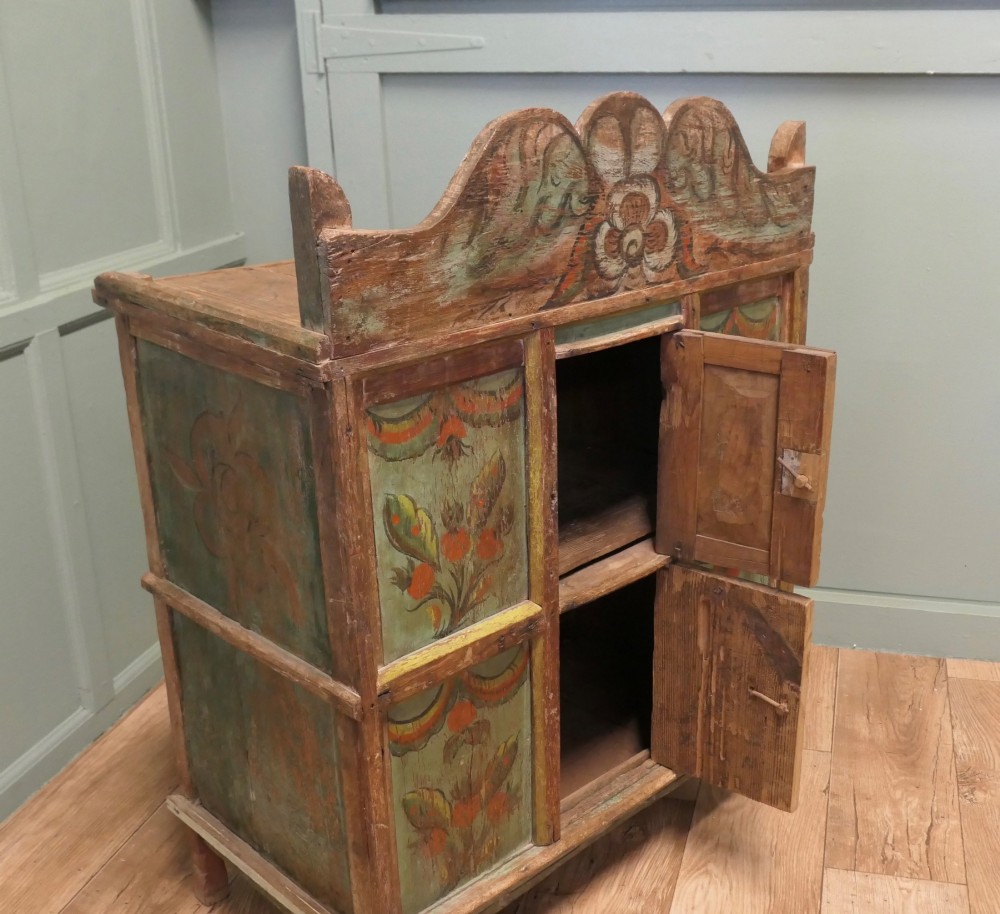 A rustic French folk art painted pine cupboard with green and orange floral panels and a scalloped gallery top. View IV