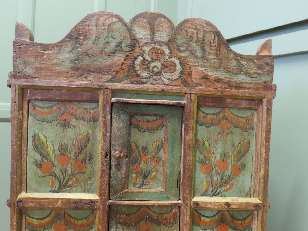 A rustic French folk art painted pine cupboard with green and orange floral panels and a scalloped gallery top. View V