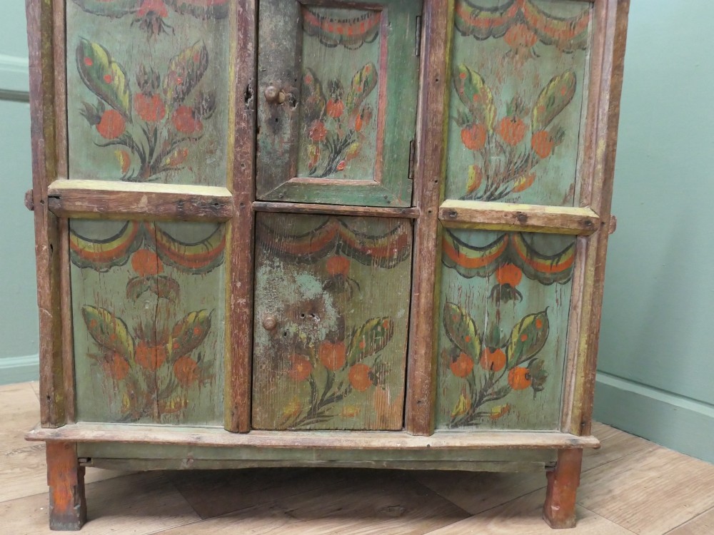 A rustic French folk art painted pine cupboard with green and orange floral panels and a scalloped gallery top. View VI