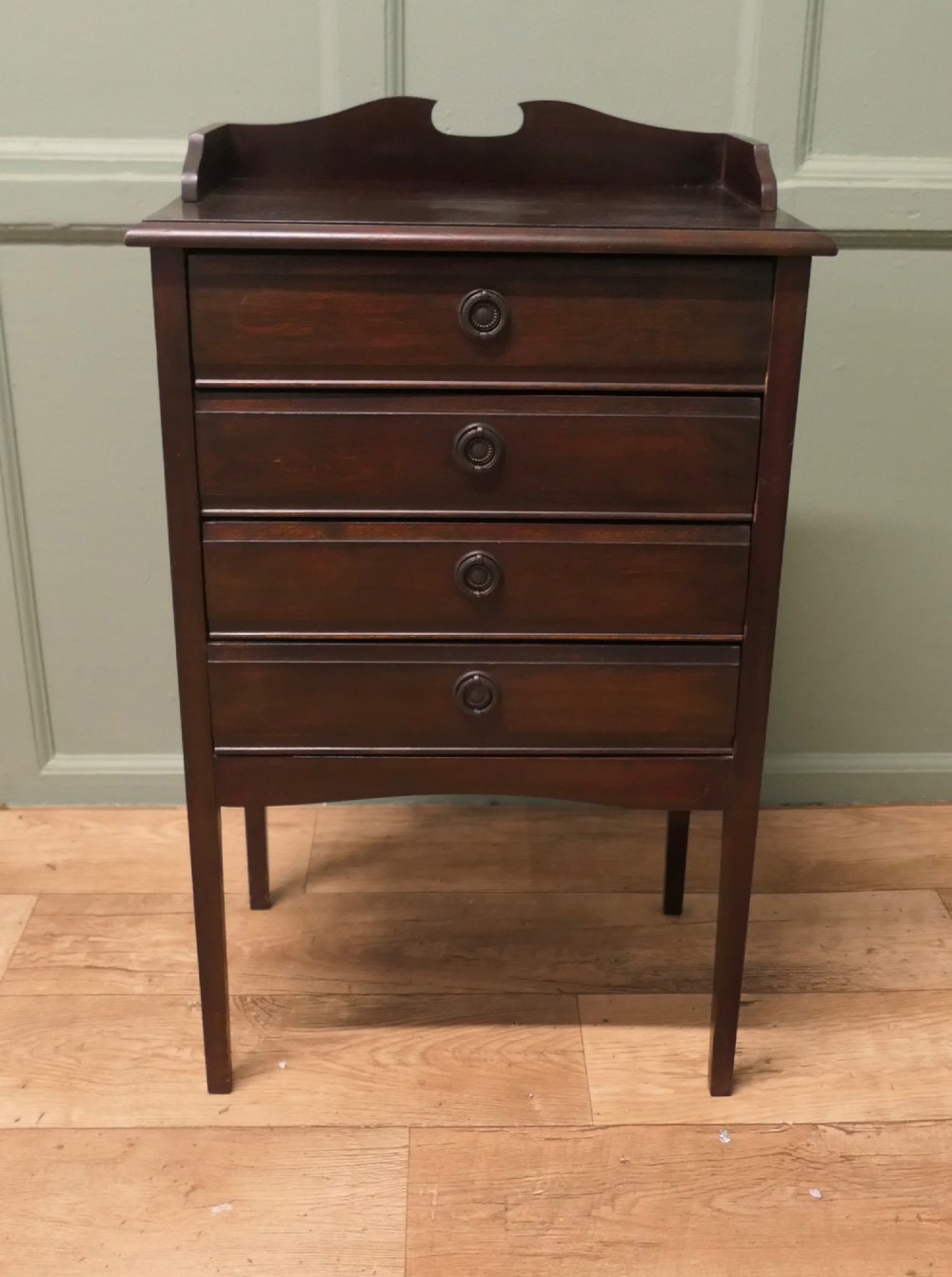 An Edwardian dark mahogany music cabinet with a raised shaped gallery back, standing on four straight legs with four drop-front drawers open to show internal slides. View II