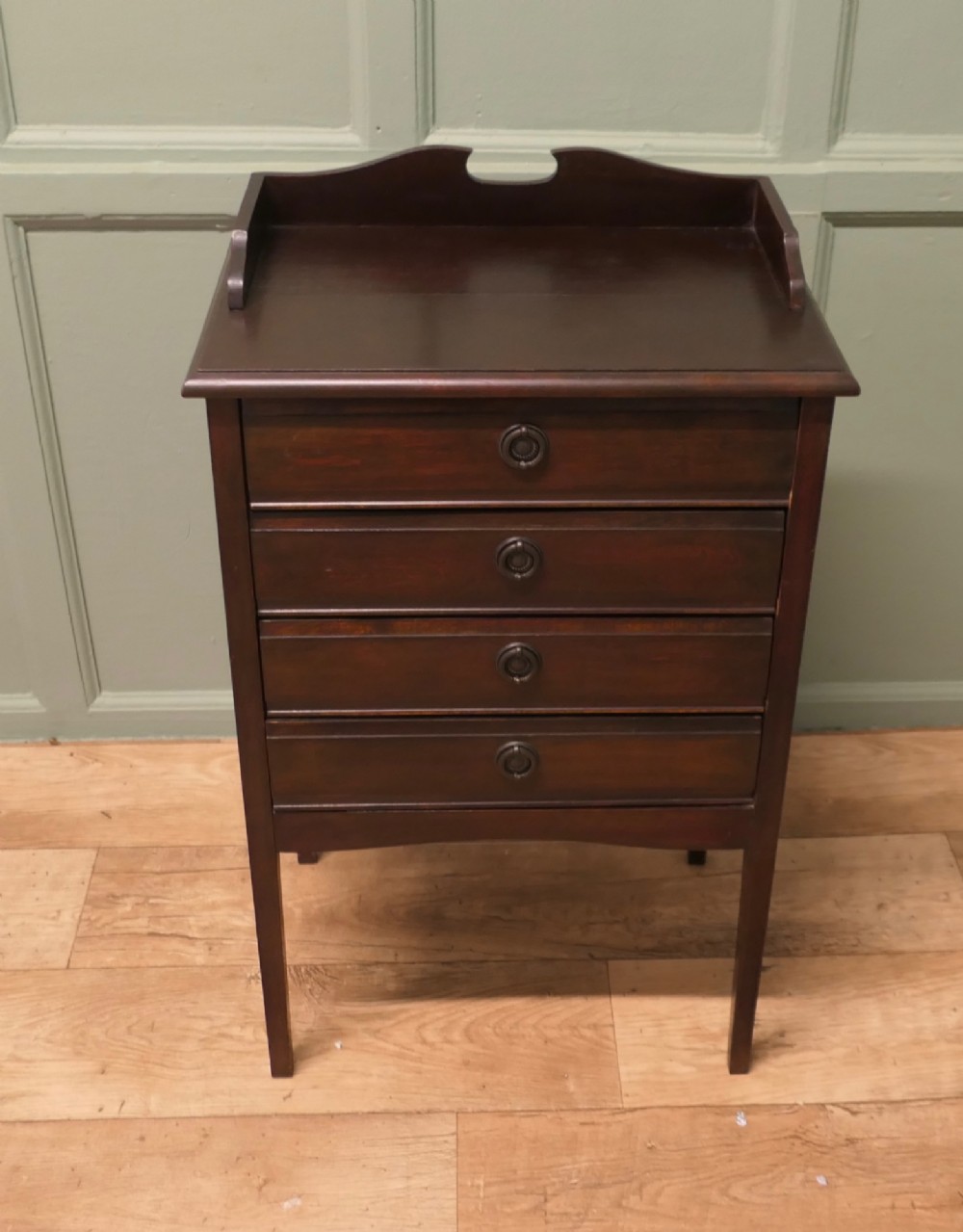 An Edwardian dark mahogany music cabinet with a raised shaped gallery back, standing on four straight legs with four drop-front drawers open to show internal slides. View III