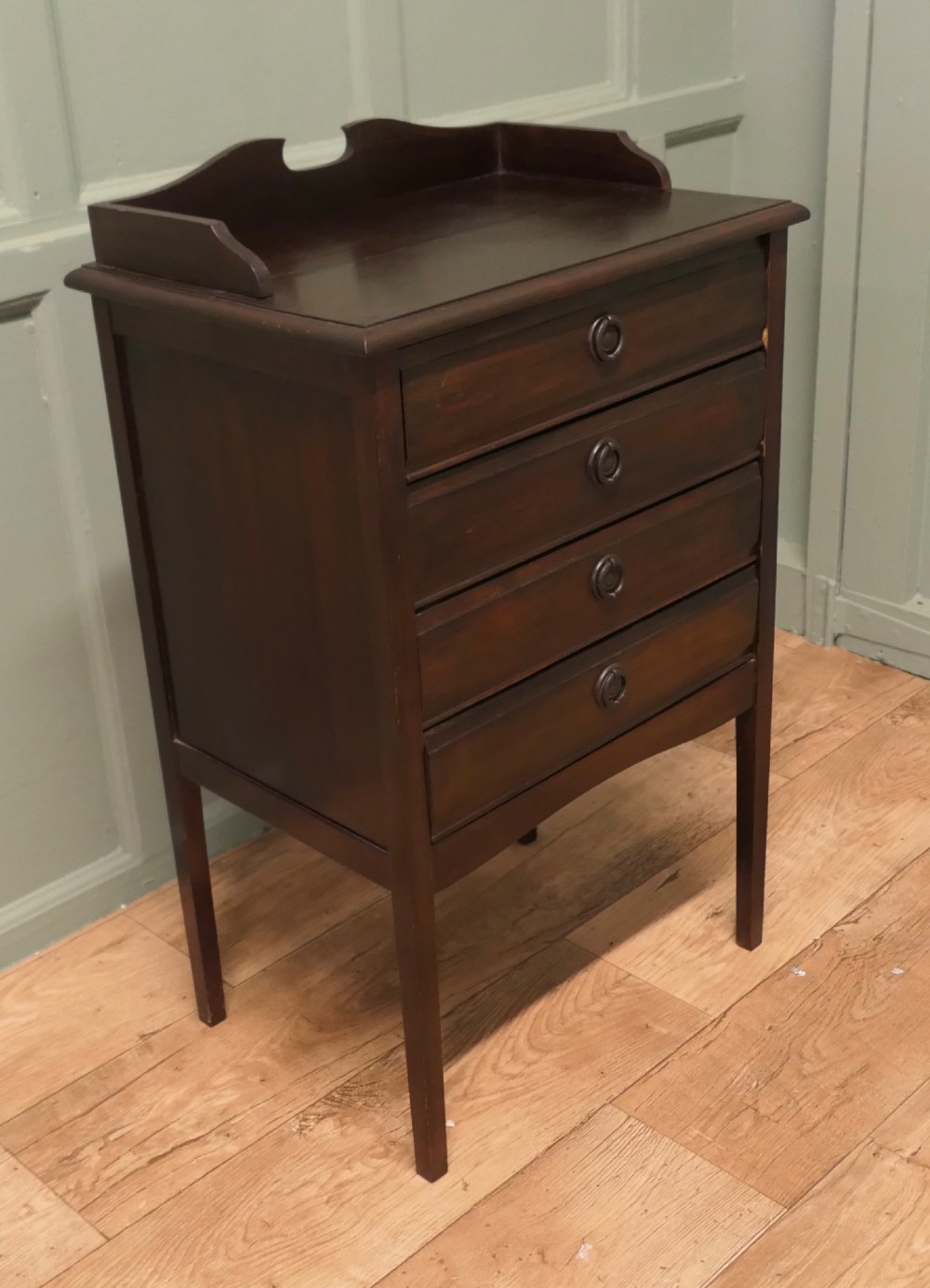 An Edwardian dark mahogany music cabinet with a raised shaped gallery back, standing on four straight legs with four drop-front drawers open to show internal slides. View V