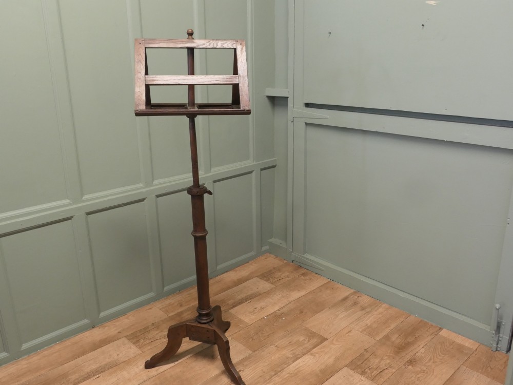 A 19th-century oak duet music stand featuring a double-sided adjustable rack resting on a turned column and tripod base.