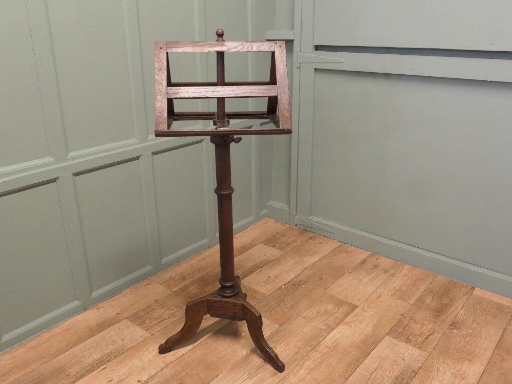 A 19th-century oak duet music stand featuring a double-sided adjustable rack resting on a turned column and tripod base. View V